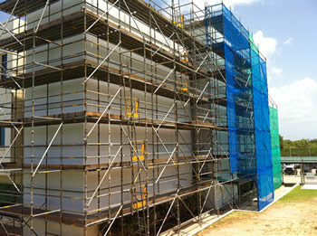 Vertical debris netting is used to circle the building site to prevent the workers and building materials falling down.